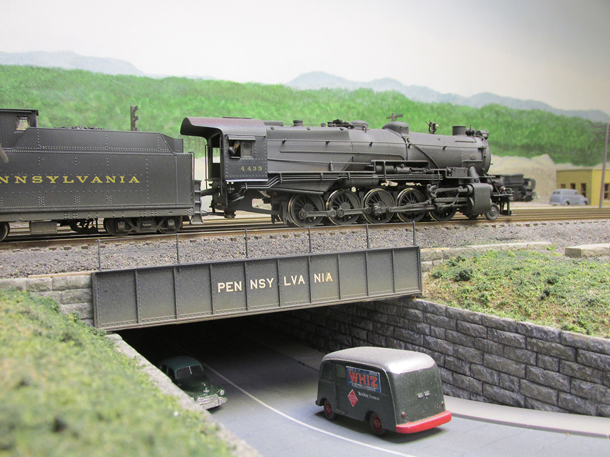 A PRR decapod crosses over main street on Curt LaRue's fine HO 1950's Pennsy layout.